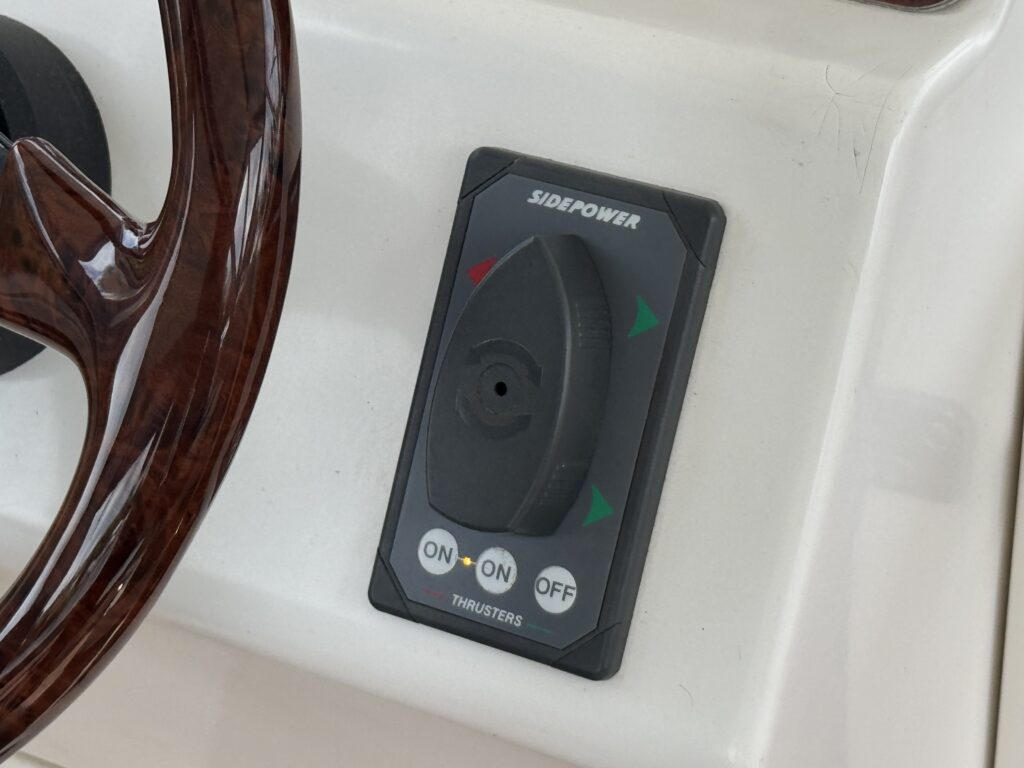 A close-up view of a control panel featuring a thruster control button labeled "SIDEPOWER." The panel has a circular joystick in the center and labeled buttons below it indicating "ON" and "OFF" positions, with green and red arrows indicating direction.