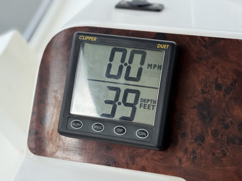 A digital display mounted on a wooden surface shows a speed of 0.0 mph and a depth of 3.9 feet. The display is framed in black with large, clear numbers for visibility.