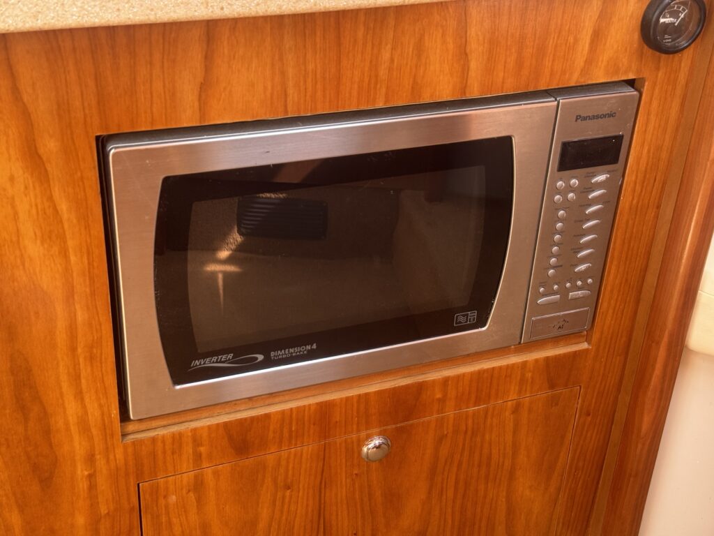 A stainless steel Panasonic microwave oven is built into a wooden cabinet. The microwave features a digital control panel on the right side, with buttons and a display for time and cooking settings.