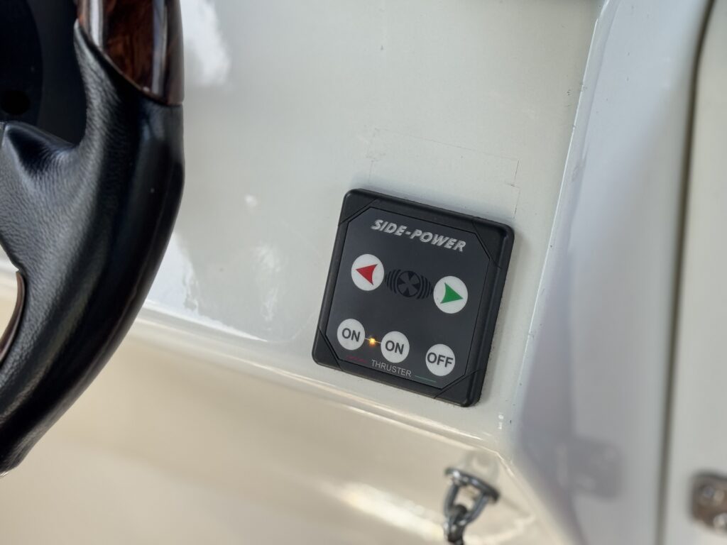 A control panel mounted on a boat's interior, featuring a black box labeled "SIDE-POWER". The panel includes three buttons marked "ON" in green, and two directional arrows colored red and green, indicating operational settings.