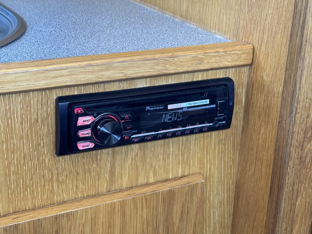A Pioneer car radio mounted in a wooden dashboard. The radio features a display showing the word 'NEWS' and various buttons and knobs for adjusting settings.