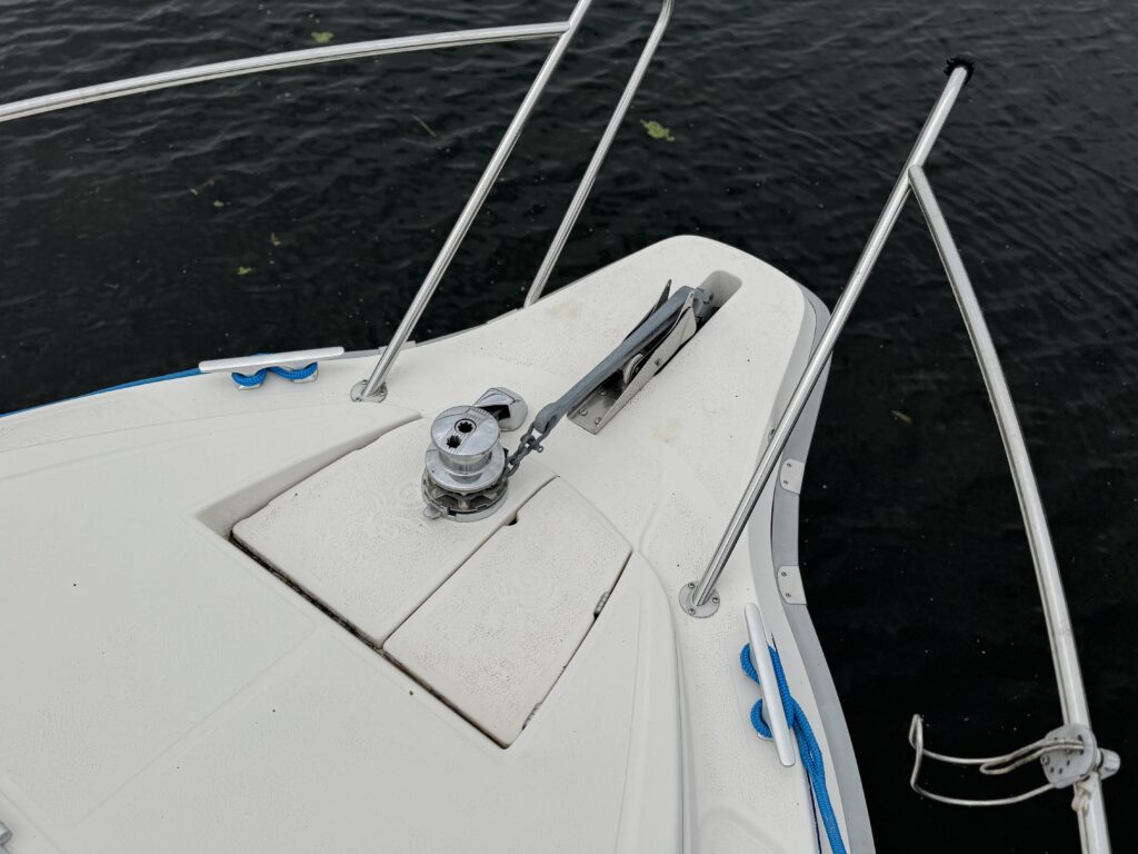The bow of a white Marex 280 Holiday boat with an anchor windlass and stainless steel railings, shown on dark water.