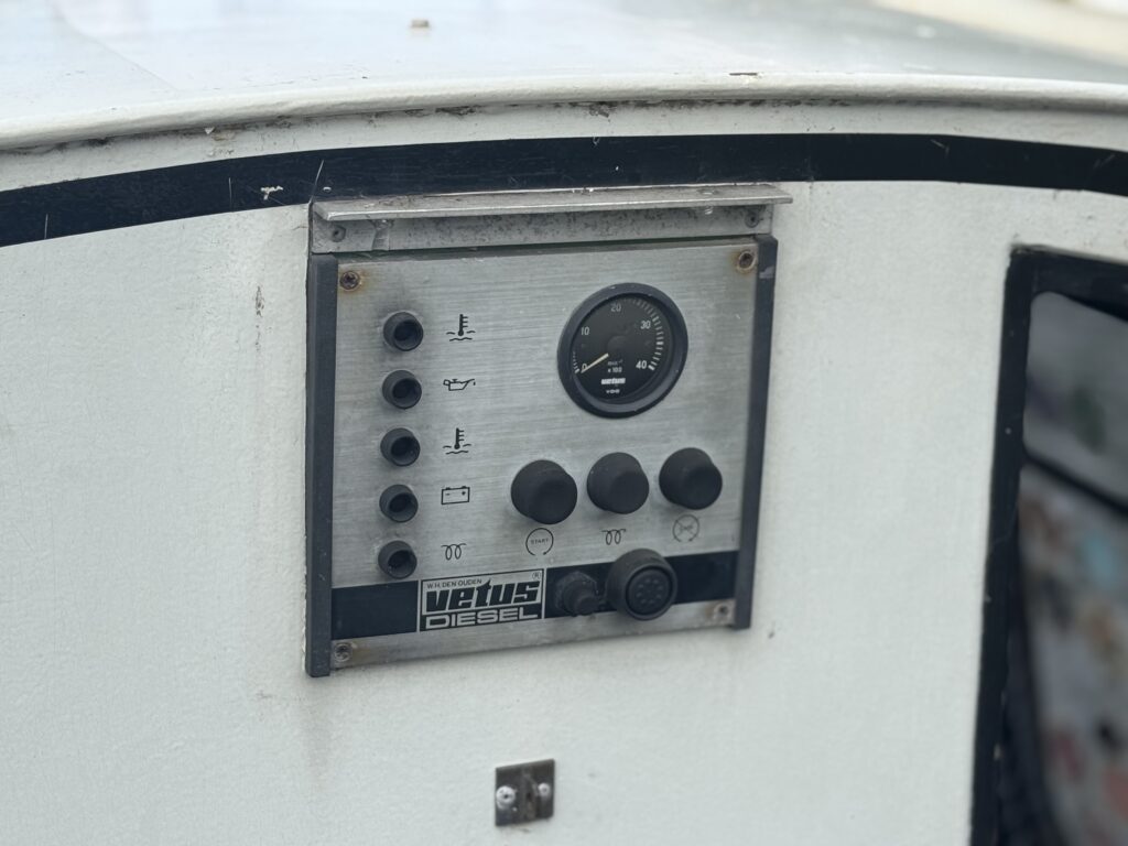 A Vetus Diesel control panel with gauges and black push buttons mounted on a white narrowboat wall.
